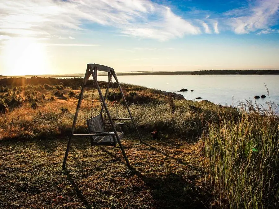 Golden hour over a calm lake with a wooden swing